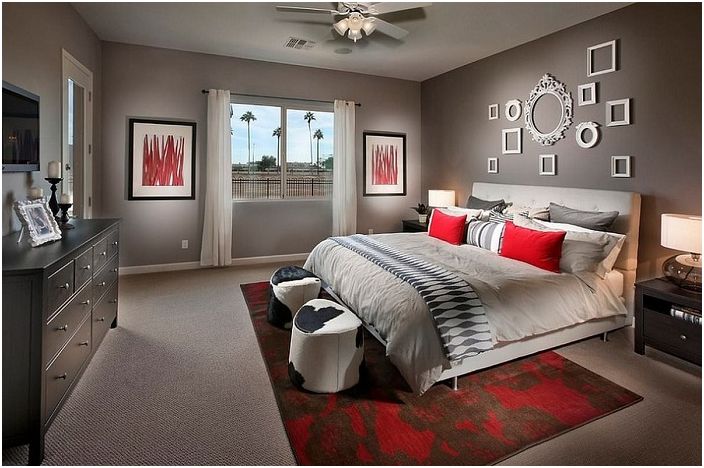 De slaapkamer in grijstinten is ingelegd met rode elementen in het interieur en witte kozijnen aan de muur, die perfect in het interieur passen.
