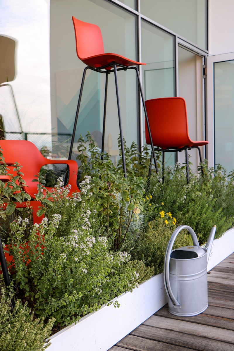 Rode en witte stoel naast groene planten.  4 trends in het aanleggen van balkontuinen die je moet kennen