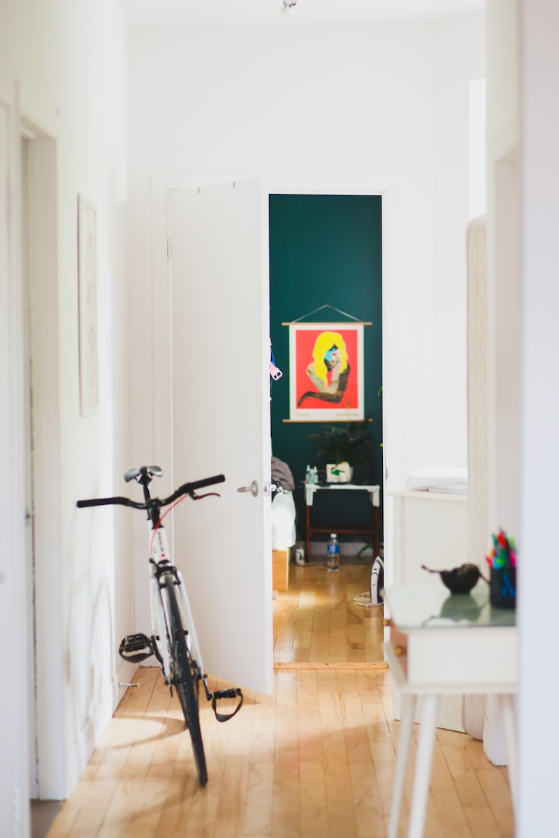Witte fiets geparkeerd in het huis.  Hoe een smalle en lange gang te versieren: 3 creatieve en praktische ideeën