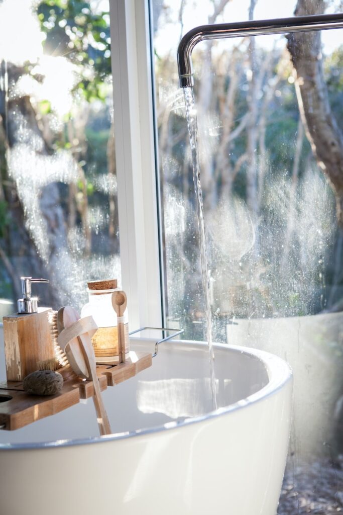 Witte keramische wastafel naast raam.  Hoe je in 5 eenvoudige stappen een schone en glanzende badkamer krijgt