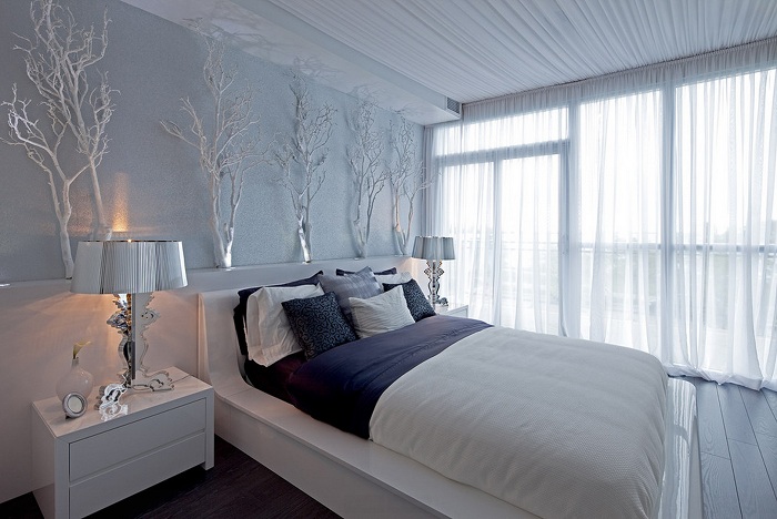 De slaapkamer in lichte kleuren wordt met succes aangevuld met versierde takken die de algehele sfeer verfrissen.